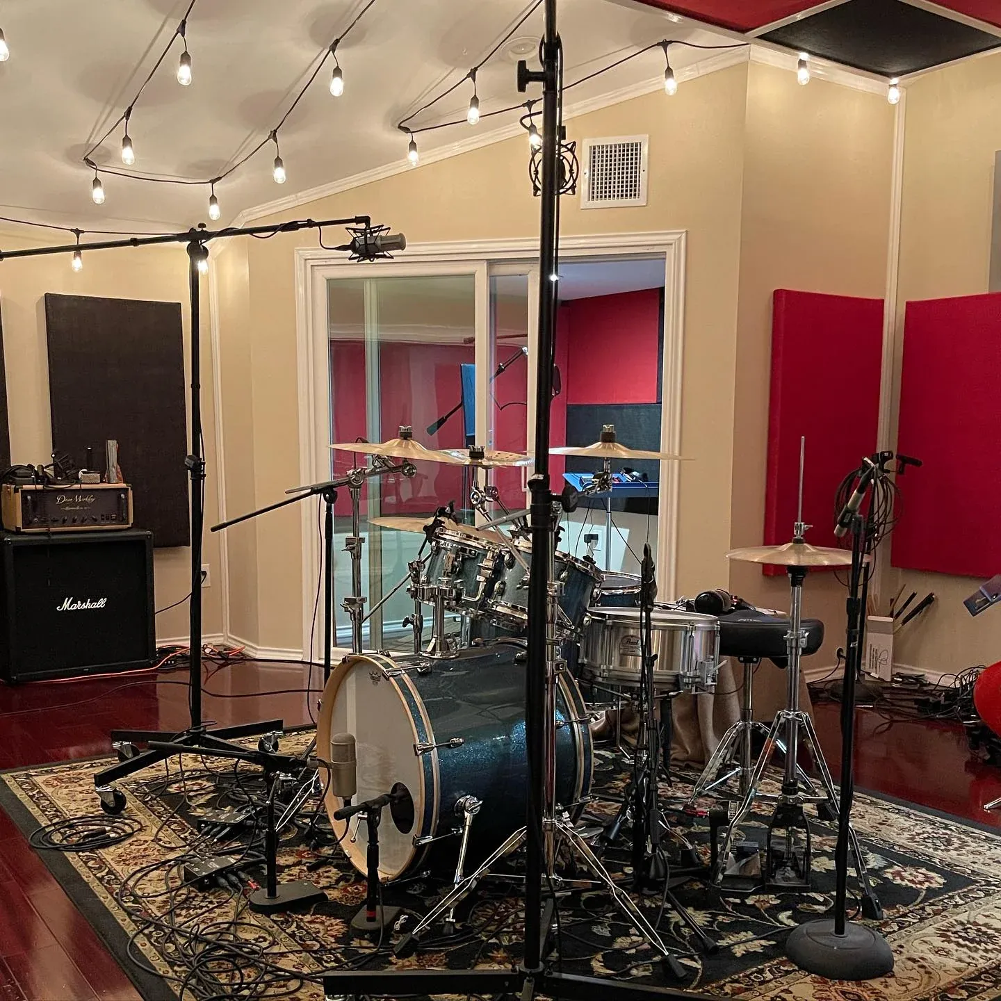 The MidWav live room with drum kit, Persian rug, wood floors and string lights